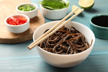 Tasty buckwheat noodles (soba) served on light blue wooden table