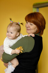 A beautiful grandmother with a one-year-old granddaughter in her arms