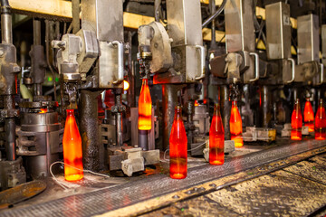 Glass factory, production of glass containers. Molten glass is blown into molds. Robotics in...