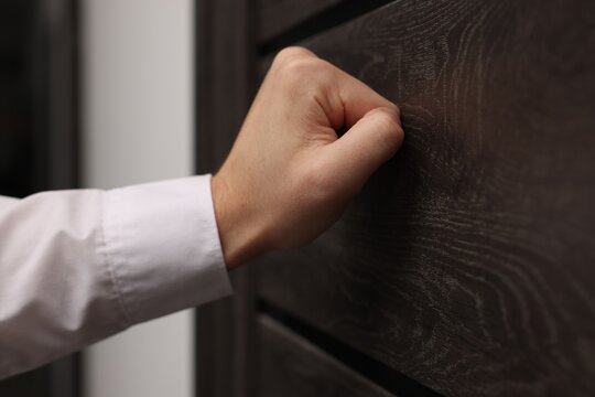 Collector knocking on door indoors, closeup view