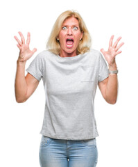 Middle age blonde woman over isolated background crazy and mad shouting and yelling with aggressive expression and arms raised. Frustration concept.