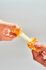 Crispy cheese fried breaded mozzarella cheese sticks stretch two hands