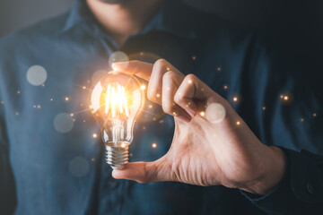 Businessman holding light bulb symbolizing creative idea and strategic thinking in...