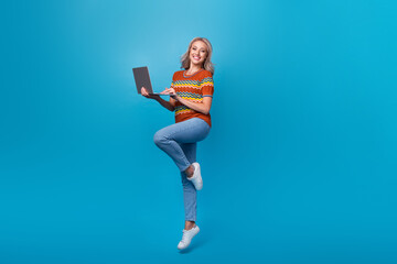 Fototapeta na wymiar Full length photo of pretty charming girl dressed print shirt jumping high working modern gadget isolated blue color background