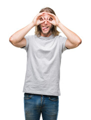 Young handsome man with long hair over isolated background doing ok gesture like binoculars sticking tongue out, eyes looking through fingers. Crazy expression.