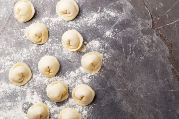 Top view on homemade tortelloni on dark stone table. Italian kitchen. Mediterranean cuisine. Selective focus.