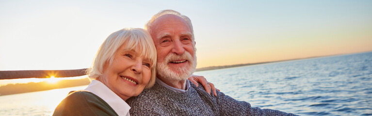 Portrait of beautiful smiling senior couple holding hands, hugging and relaxing together while...