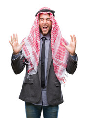 Young handsome arabian man with long hair wearing keffiyeh over isolated background celebrating mad and crazy for success with arms raised and closed eyes screaming excited. Winner concept