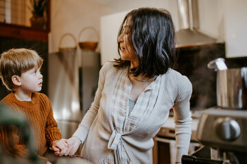 Boy and mother talking together in home kitchen