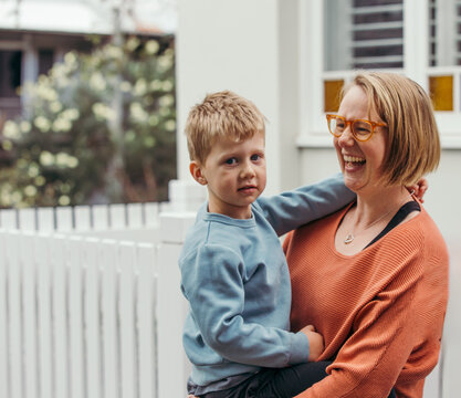Mum laughing holding son outside home