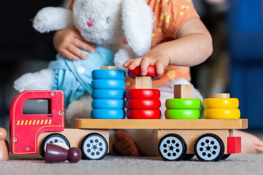 Toddler placing coloured shape on correct peg of wooden toy truck