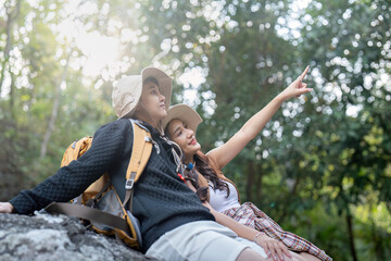 Cheerful romantic lesbian couple traveler with backpacks and siting relaxing while hiking in the...