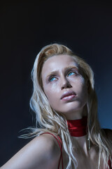 portrait of fashionable young woman with glitter in red dress posing alluringly and looking away