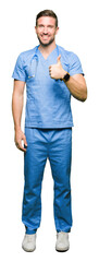 Handsome doctor man wearing medical uniform over isolated background doing happy thumbs up gesture...