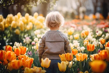 Tuinposter Back view of small girl child in field of tulip spring flowers © Firn