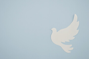 White paper origami bird on blue background. World Day of Peace. Day Against Humiliation....