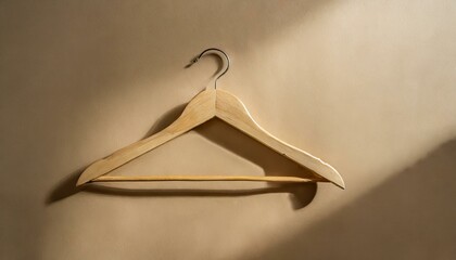coat hanger.a wooden hanger against a warm beige backdrop. The image should evoke a sense of simplicity and home organization, making it suitable for interior design or lifestyle content.