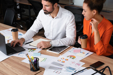Happy young entrepreneurs having a discussion while sitting together at a table.