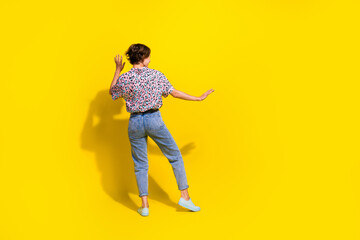 Full length rear behind photo of overjoyed satisfied person dancing empty space isolated on yellow color background