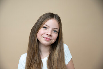 beautiful, cool, cute tween, teenager girl with long hair is posing in front of brown background