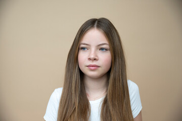 Obraz premium beautiful, cool, cute tween, teenager girl with long hair is posing in front of brown background