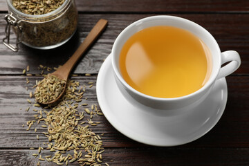 Fennel tea in cup and seeds on wooden table, closeup