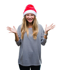 Fototapeta na wymiar Young beautiful blonde woman wearing christmas hat over isolated background celebrating crazy and amazed for success with arms raised and open eyes screaming excited. Winner concept