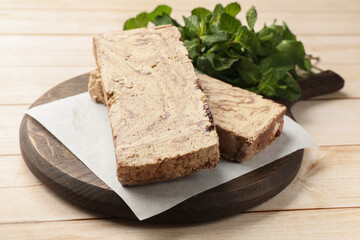 Pieces of tasty chocolate halva with mint on wooden table, closeup