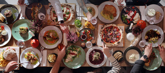Eating together. Table full of food, from above, wide view. Enjoying food, dining with family, friends.