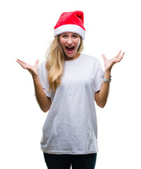 Obraz na płótnie Canvas Young beautiful blonde woman wearing christmas hat over isolated background celebrating crazy and amazed for success with arms raised and open eyes screaming excited. Winner concept