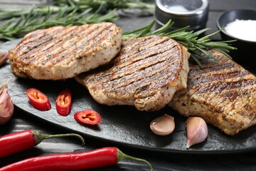 Delicious grilled pork steaks with spices on table, closeup
