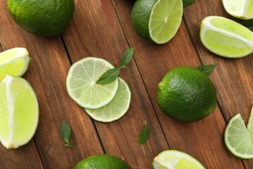 Flat lay composition with fresh limes and leaves on wooden table