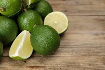 Pile of fresh limes on wooden table, closeup. Space for text
