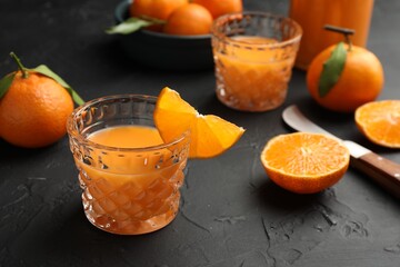 Tasty tangerine liqueur in glasses and fresh citrus fruits on black textured table