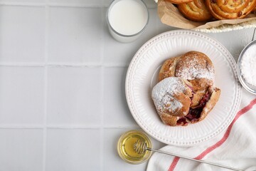 Delicious rolls with sugar powder and berries on white tiled table, flat lay with space for text. Sweet buns