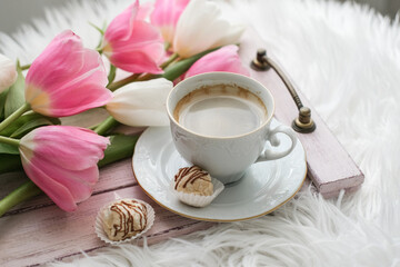Cup of coffee, cake and bouquet of tulips on a wooden tray