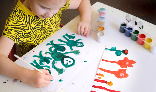 Child girl painting friendly funny aliens, Creative activities with a child to develop creative imagination, have a fun time
