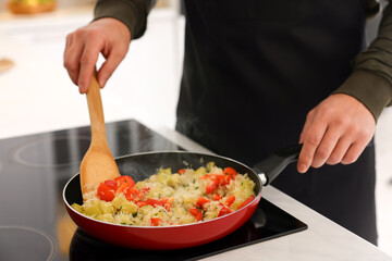 Man cooking dish on cooktop indoors, closeup