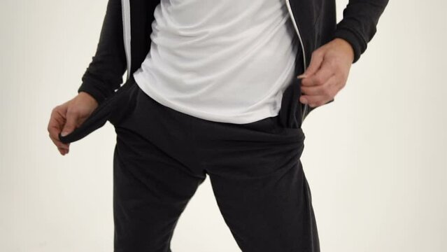 The man takes out the empty pockets of his sports pants and starts to dance. Empty pockets of poor sportsman. The player lost everything, but he does not get upset. The thing is lost from the pocket.
