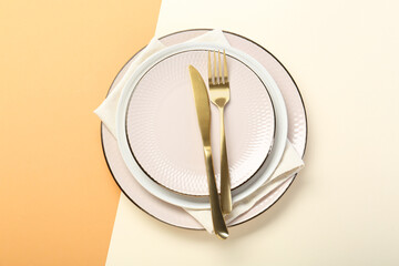 Ceramic plates, cutlery and napkin on color background, top view