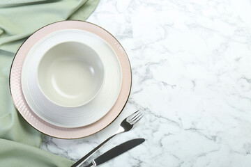 Clean plates, bowl and cutlery on white marble table, flat lay. Space for text