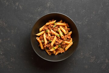 Penne pasta with minced meat, tomato sauce and greens
