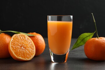 Delicious tangerine liqueur in glass and fresh fruits on grey table