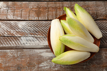 Fresh raw Belgian endives (chicory) on wooden table, top view. Space for text - obrazy, fototapety, plakaty