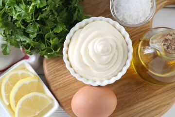 Fresh mayonnaise sauce in bowl and ingredients on table, flat lay