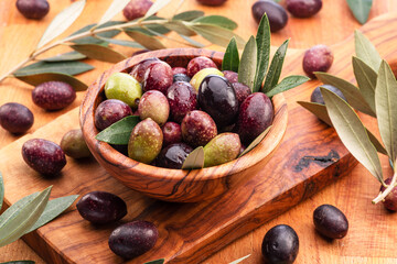Fresh olives in wooden bowl on the wood background.