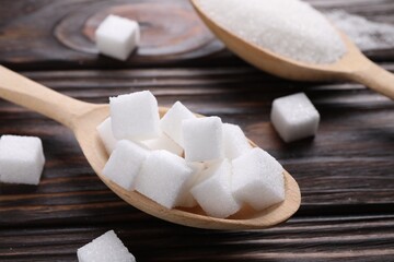 Spoons with different types of white sugar on wooden table, closeup