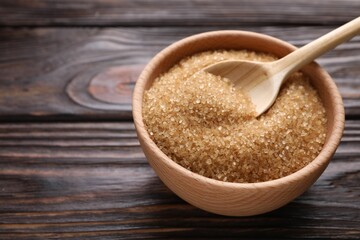 Bowl and spoon with brown sugar on wooden table, closeup. Space for text