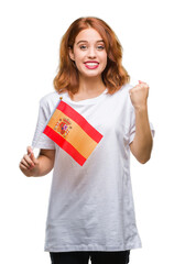 Young beautiful woman holding flag of spain over isolated background screaming proud and celebrating victory and success very excited, cheering emotion