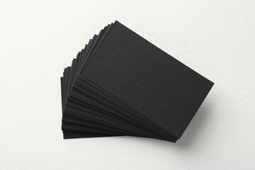 Blank black business cards on white table, top view